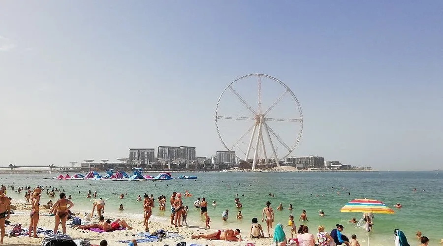 People enjoying JBR Beach in Dubai, walking along the shore and relaxing by the sea