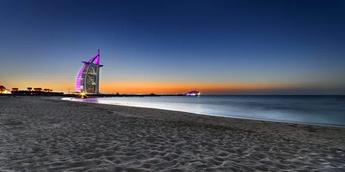 Night beaches in Dubai with city lights, evening swim, and people walking along the shore
