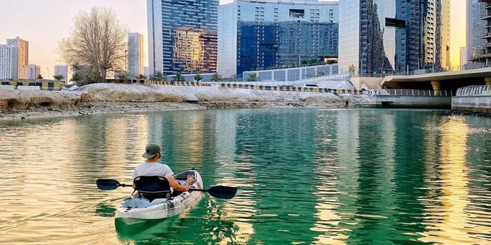 People kayaking on the canal at Reem Central Park, Abu Dhabi, with scenic waterfront and urban park background